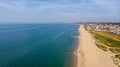 A beautiful aerial seaside view with sandy beach, crystal blue water, groynes breakwaters and green vegetation dunes along a