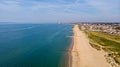 A beautiful aerial seaside view with sandy beach, crystal blue water, groynes breakwaters and green vegetation dunes along a