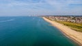 A beautiful aerial seaside view with sandy beach, crystal blue water, groynes breakwaters and green vegetation dunes along a