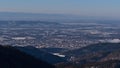 Aerial view of city Freiburg im Breisgau, Kaiserstuhl hills and Vosges on horizon in winter with snow-covered landscape. Royalty Free Stock Photo