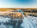 Beautiful aerial view of snow covered fields with a road among trees. Rime ice and hoar frost covering trees