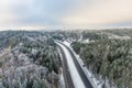 Beautiful aerial view of snow covered fields with a two-lane road among trees. Rime ice and hoar frost covering trees. Scenic