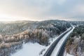 Beautiful aerial view of snow covered fields with a two-lane road among trees. Rime ice and hoar frost covering trees. Scenic