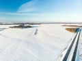 Beautiful aerial view of snow covered fields with a two-lane road among trees. Rime ice and hoar frost covering trees