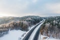 Beautiful aerial view of snow covered fields with a two-lane road among trees. Rime ice and hoar frost covering trees. Scenic