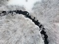 Beautiful aerial view of snow covered pine forests and a river winding among trees. Rime ice and hoar frost covering trees. Winter