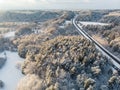 Beautiful aerial view of snow covered pine forests and a road winding among trees. Rime ice and hoar frost covering trees. Winter