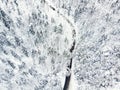 Beautiful aerial view of snow covered pine forests and a road winding among trees. Rime ice and hoar frost covering trees. Scenic Royalty Free Stock Photo