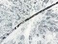 Beautiful aerial view of snow covered pine forests and a road winding among trees. Rime ice and hoar frost covering trees. Scenic