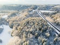 Beautiful aerial view of snow covered pine forests and a road winding among trees. Rime ice and hoar frost covering trees. Scenic