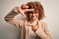 Beautiful african american businesswoman wearing glasses over isolated white background smiling making frame with hands and Royalty Free Stock Photo