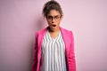 Beautiful african american businesswoman wearing jacket and glasses over pink background afraid and shocked with surprise and Royalty Free Stock Photo