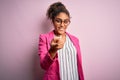 Beautiful african american businesswoman wearing jacket and glasses over pink background Beckoning come here gesture with hand