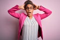 Beautiful african american businesswoman wearing jacket and glasses over pink background Crazy and scared with hands on head, Royalty Free Stock Photo