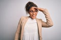 Beautiful african american businesswoman wearing jacket and glasses over white background very happy and smiling looking far away Royalty Free Stock Photo