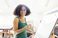 Beautiful African American girl with dark curly hair standing near board and giving presentation to colleagues in office Royalty Free Stock Photo