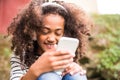 Beautiful african american girl with smart phone and earphones. Royalty Free Stock Photo