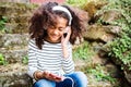 Beautiful african american girl with smart phone and earphones. Royalty Free Stock Photo