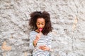 Beautiful african american girl with smart phone, eating lollipo Royalty Free Stock Photo