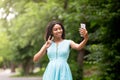 Beautiful African American girl taking selfie or communicating online on cellphone at park Royalty Free Stock Photo