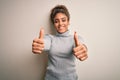 Beautiful african american girl wearing turtleneck sweater standing over white background approving doing positive gesture with Royalty Free Stock Photo