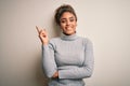 Beautiful african american girl wearing turtleneck sweater standing over white background with a big smile on face, pointing with Royalty Free Stock Photo