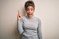 Beautiful african american girl wearing turtleneck sweater standing over white background pointing finger up with successful idea Royalty Free Stock Photo