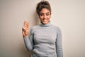 Beautiful african american girl wearing turtleneck sweater standing over white background showing and pointing up with fingers Royalty Free Stock Photo
