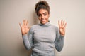 Beautiful african american girl wearing turtleneck sweater standing over white background showing and pointing up with fingers Royalty Free Stock Photo