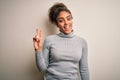 Beautiful african american girl wearing turtleneck sweater standing over white background showing and pointing up with fingers Royalty Free Stock Photo