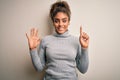 Beautiful african american girl wearing turtleneck sweater standing over white background showing and pointing up with fingers Royalty Free Stock Photo