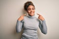 Beautiful african american girl wearing turtleneck sweater standing over white background smiling cheerful showing and pointing Royalty Free Stock Photo