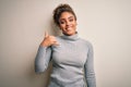 Beautiful african american girl wearing turtleneck sweater standing over white background smiling doing phone gesture with hand Royalty Free Stock Photo