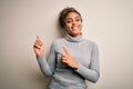 Beautiful african american girl wearing turtleneck sweater standing over white background smiling and looking at the camera Royalty Free Stock Photo