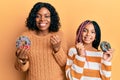 Beautiful african american mother and daughter holding donuts screaming proud, celebrating victory and success very excited with Royalty Free Stock Photo
