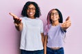 Beautiful african american mother and daughter wearing casual clothes and glasses smiling friendly offering handshake as greeting Royalty Free Stock Photo