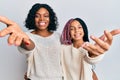 Beautiful african american mother and daughter wearing casual clothes and hugging smiling friendly offering handshake as greeting Royalty Free Stock Photo