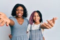 Beautiful african american mother and daughter wearing casual clothes and hugging smiling friendly offering handshake as greeting Royalty Free Stock Photo