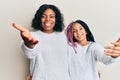 Beautiful african american mother and daughter wearing casual winter sweater smiling friendly offering handshake as greeting and Royalty Free Stock Photo