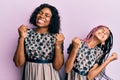 Beautiful african american mother and daughter wearing sexy party dress very happy and excited doing winner gesture with arms Royalty Free Stock Photo