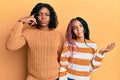 Beautiful african american mother and daughter wearing wool winter sweater confused and annoyed with open palm showing copy space