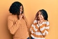 Beautiful african american mother and daughter wearing wool winter sweater laughing nervous and excited with hands on chin looking Royalty Free Stock Photo