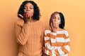 Beautiful african american mother and daughter wearing wool winter sweater looking at the camera blowing a kiss with hand on air Royalty Free Stock Photo