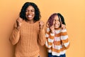 Beautiful african american mother and daughter wearing wool winter sweater very happy and excited doing winner gesture with arms Royalty Free Stock Photo
