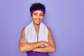 Beautiful african american sporty woman doing sport wearing towel over purple background happy face smiling with crossed arms Royalty Free Stock Photo