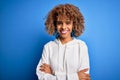 Beautiful african american sporty woman wearing casual sweatshirt over blue background happy face smiling with crossed arms Royalty Free Stock Photo