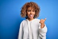 Beautiful african american sporty woman wearing casual sweatshirt over blue background smiling with happy face looking and Royalty Free Stock Photo