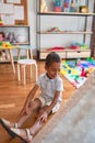 Beautiful african american toddler putting on shoes outside tipi at kindergarten