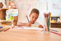 Beautiful african american toddler sitting drawing using paper and pencils on desk at kindergarten Royalty Free Stock Photo