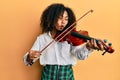 Beautiful african american woman with afro hair playing classical violin making fish face with mouth and squinting eyes, crazy and